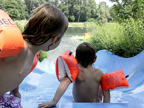 Kinder benutzen Wasserrutsche im Freibad