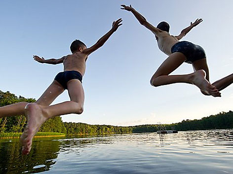 Zwei Jungen springen in einen See