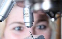 Labormitarbeiter untersucht Mikrobohrer im Mikroskop