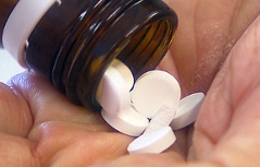 Tabletten werden aus Fläschchen in die Hand geschüttet