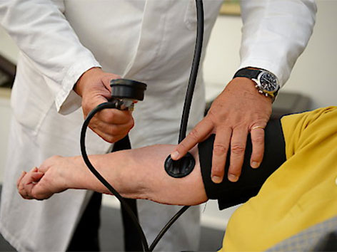 Arzt misst Blutdruck bei einer Patientin