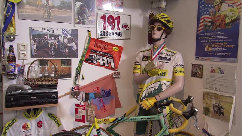 Das Bild zeigt eine Schaufensterpuppe mit dem Fahrrad-Dress von Wolfgang Faschin, außerdem sind die Medaille und das Rennrad zu sehen.
