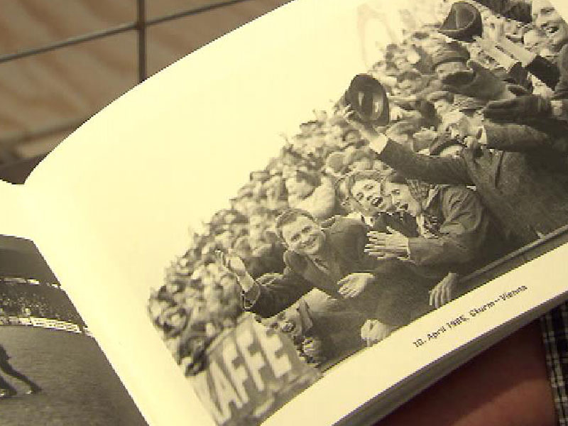 In einem Buch sind auf einem schwarz-weiß Foto jubelnde Fussballfans in der Gruabn zu sehen