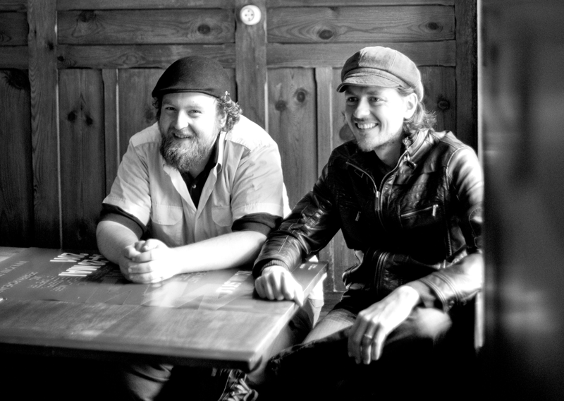 Roland und Georg Gratzer sitzen an einem Tisch. Das Foto ist schwarz-weiß.